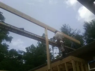 Carpenter setting a ridge beam over a new addition frame — Ice Dam Removal by Roofing Brothers in Saint Anthony