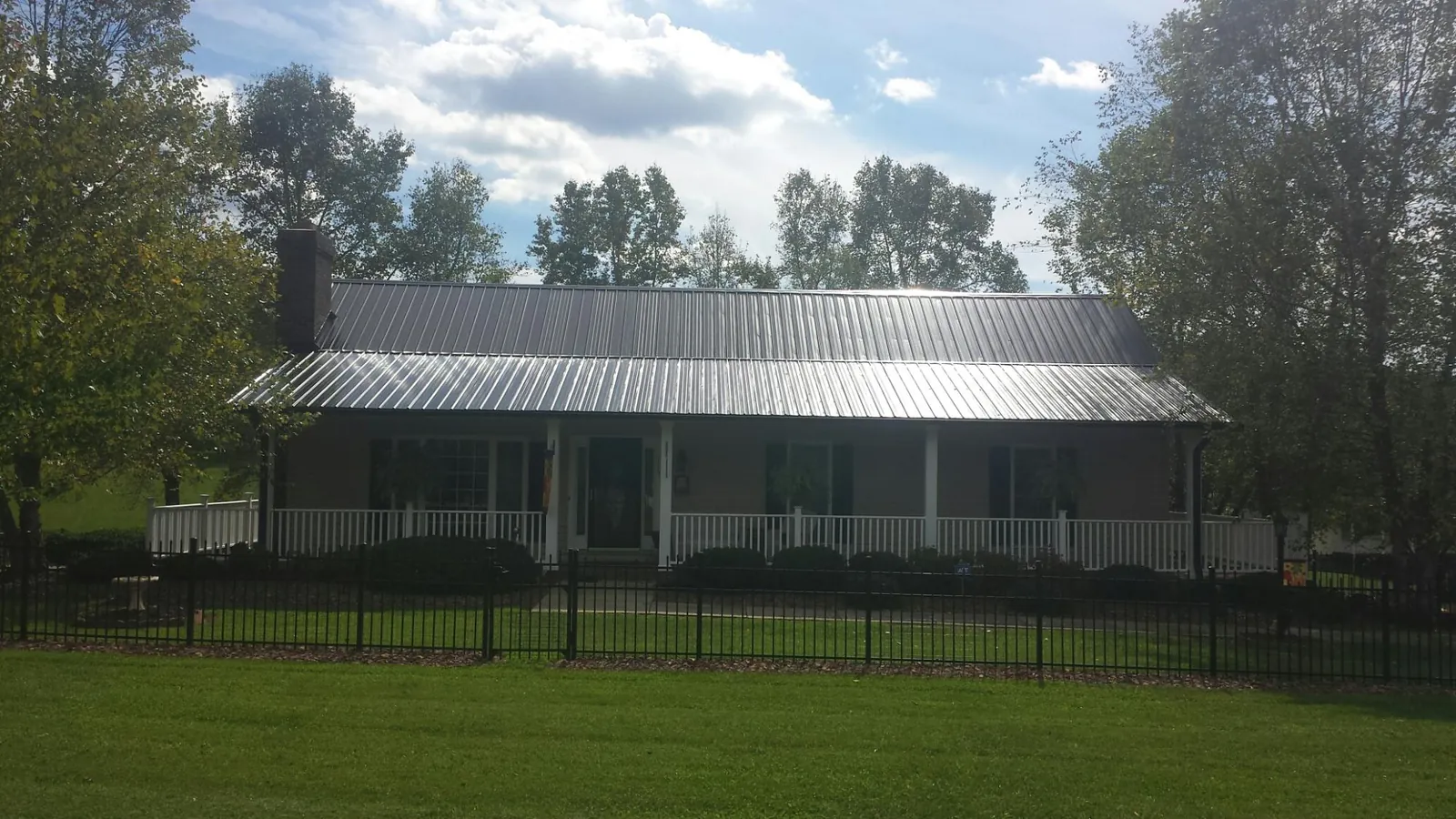 Gray metal roof on a brick ranch with a full width front porch — Gutter Guard Installation work by our crew in Saint Anthony